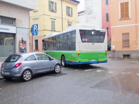 Silver hatchback car parked next to a green and white public transport bus Stock Photos