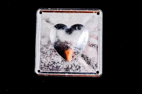 A silver heart with a brown center is reflected in a window Foto stock