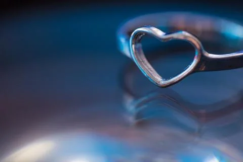 Silver heart shape ring with black blue background Stock Photos