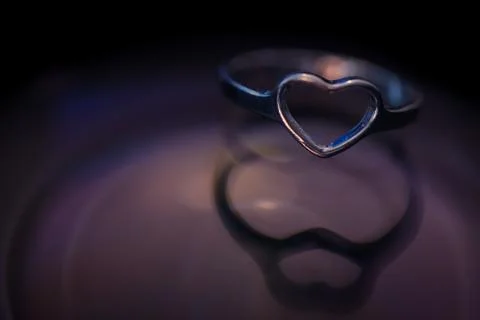 Silver heart shape ring with black and purple background Stock Photos