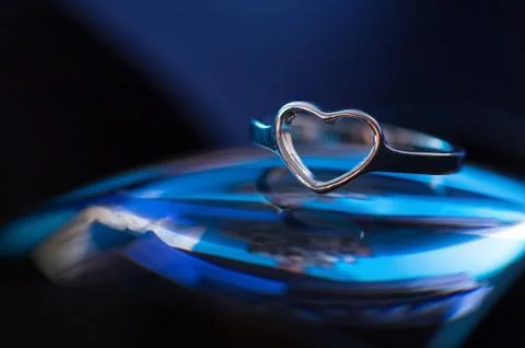 Silver heart shape ring with blue background Stock Photos