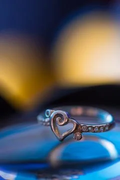 Silver heart shape ring with blue and yellow background Stock Photos