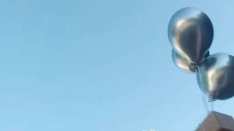 Silver helium balloons fly down attached to grey box Video stock 170155245