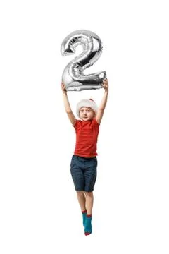 Silver inflatable number 2 in the hands of a jumping boy in a red hat. White  Stock-Fotos