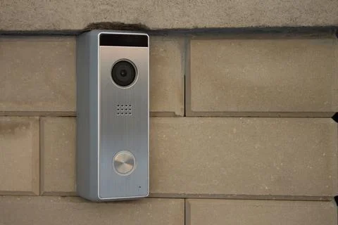 Silver intercom panel with video camera on a brick beige fence pillar of a pr Foto stock