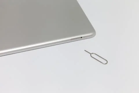 Silver inverted tablet. Visible tray for the SIM card and the key to open Stock Photos