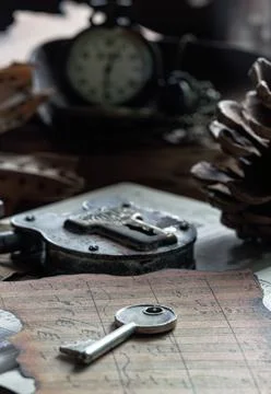 A silver key sits in the foreground on charred, weathered sheet music. Behi.. Stock Photos