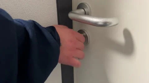Silver key unlocks a white door person with dark blue sweater Vídeos de archivo 236984374