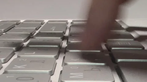 Silver keyboard close-up. Keys display "q", "w", "e", and symbols. Stock Footage 345398949