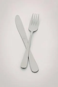 Silver knife and fork crossed over each other Stock Photos