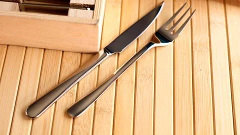Silver knife and fork placed neatly on wooden surface, emphasizing sleek design Stock Photos