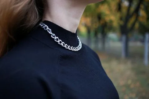 A silver large chain hangs around the girl's neck Stock Photos