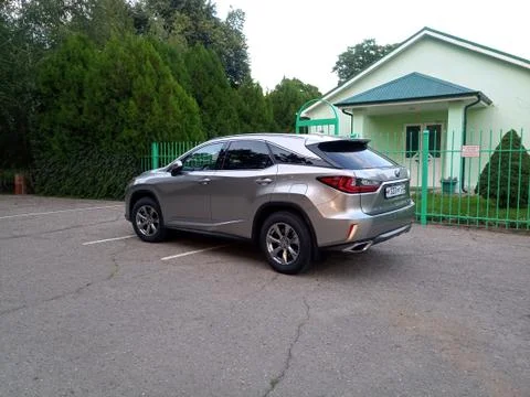 Silver Lexus NX car in a parking lot near a building in the park. Fotos de archivo