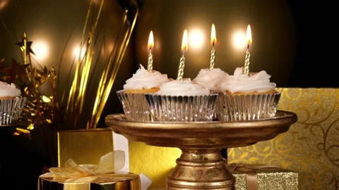 Silver Lined Cupcakes with Candles on a Tray at a Table at a Gold Party Stock Footage 345197397