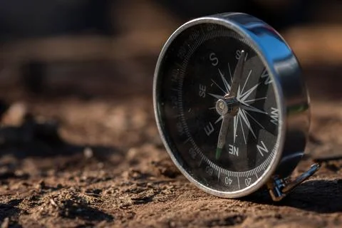 A silver metal compass the arrow is pointing to North, the background of the ear Stockfoto's