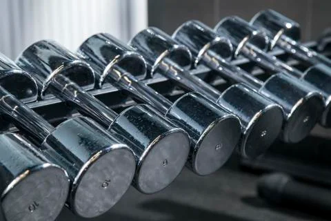 Silver metal dumbbell set. Close up many metal dumbbells on rack in gym Stock Photos