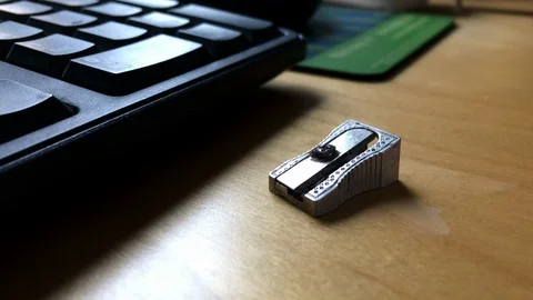 Silver metal pencil sharpener lying on sun lit office desk next to keyboard Stock-Footage 107607478
