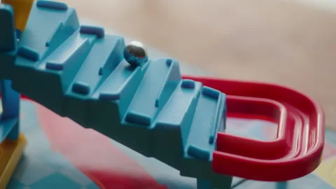 Silver, metallic marble rolling down a zig-zagging blue and red slide 스톡 동영상 328126215