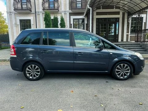 Silver minivan parked outside an elegant building surrounded by greenery on.. Stock-Fotos