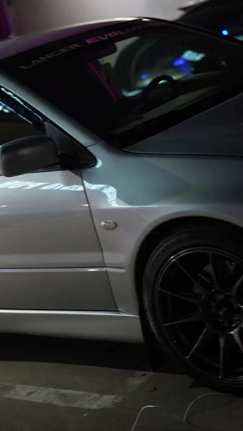 Silver mitsubishi lancer evolution custom car at night Stock Footage 333570313