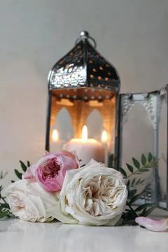 Silver Moroccan, Arabic lantern with burning candle. Pink roses flowers on white Stockfoto's