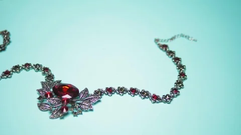 Silver necklace with ruby on a blue background. fashion design Stock Footage 123688507
