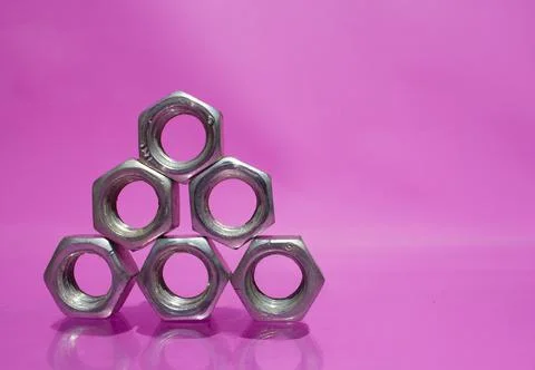 Silver nuts on a pink background in the shape of a triangle. Stock Photos