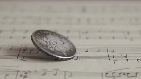 Silver Old Coin Falls And Spins On The Sheet Of Music Close Up. Spinning Stock Footage 156539637