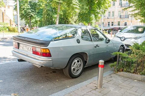 Silver or gray, two-door compact car parked on urban street Worn appearance.. Stock Photos