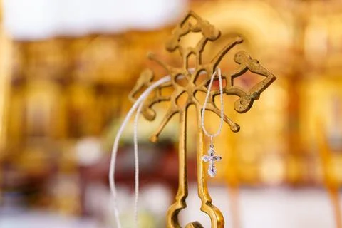 A silver pectoral cross on a string on a large gold cross of the baptismal font. 스톡 사진