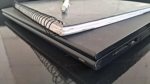 Silver pen resting on a spiral notebook atop black laptop Stock Photos