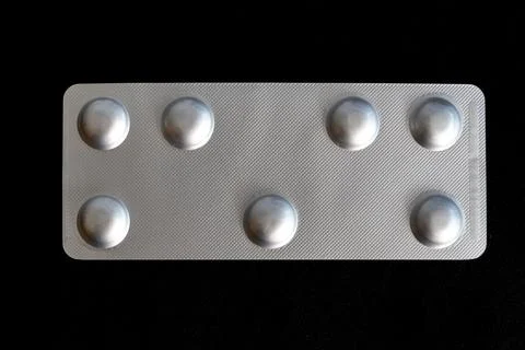 A silver pill container sits on a black background Foto stock
