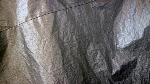 Silver plastic tarp texture creating abstract crumpled reflections and mate.. Stock Photos