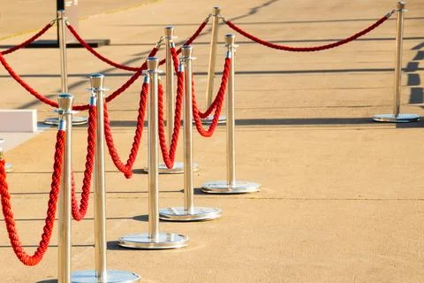 Silver plated barrier posts with red velvet ropes with red event carpet. Stock Photos