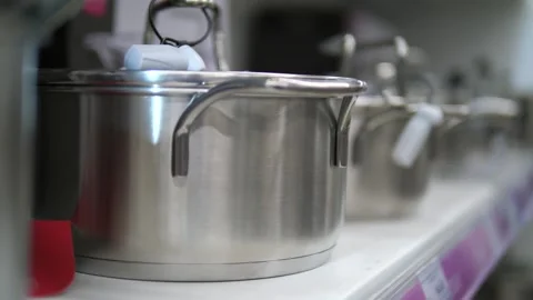 Silver pots with lids on a store shelf. New pots standing in a row. Stock Footage 313651448
