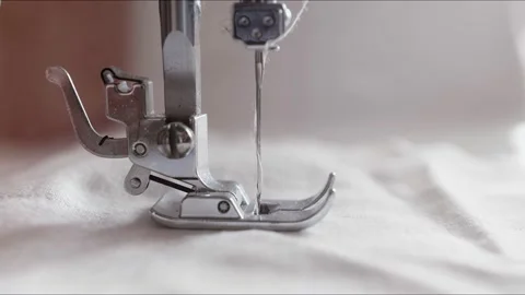The silver presser foot of the sewing machine presses the fabric and stitches it Stock Footage 133639651