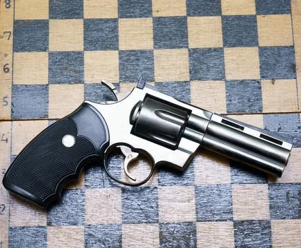 Silver revolver placed on a checkerboard pattern background in an indoor setting Stock Photos