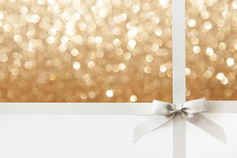 Silver ribbon with a bow as a gift on a white and gold Shiny background Stock Photos
