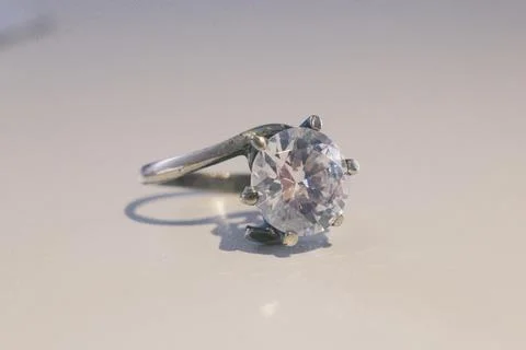 Silver ring with brilliant round gem on smooth light surface indoors Stock Photos
