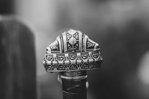 A silver ring with a cross on it sits on a wooden table Stock Photos