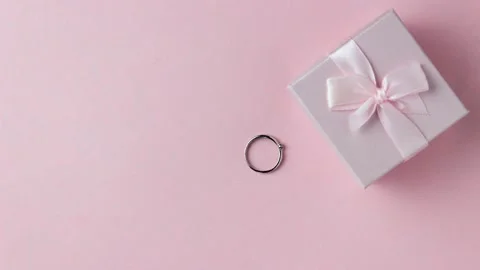 Silver ring go in a pink gift box on a pink background. Cute stop motion video. Stock Footage 155024077