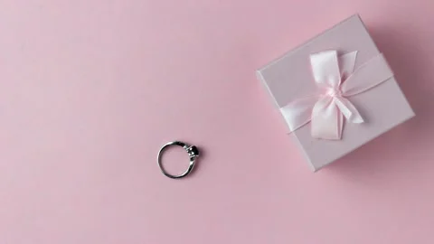 Silver ring go in a pink gift box on a pink background. Cute stop motion video. Stock Footage 155860540