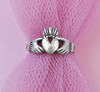 Silver ring with a heart on a pink background close-up. Stock Photos