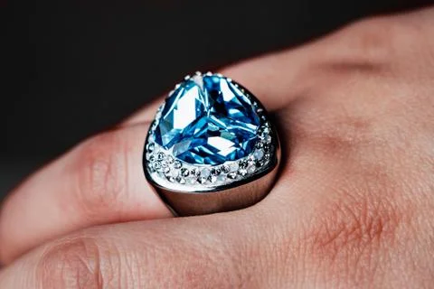 A silver ring on his hand with a large blue gem and small stones around it. Stock Photos