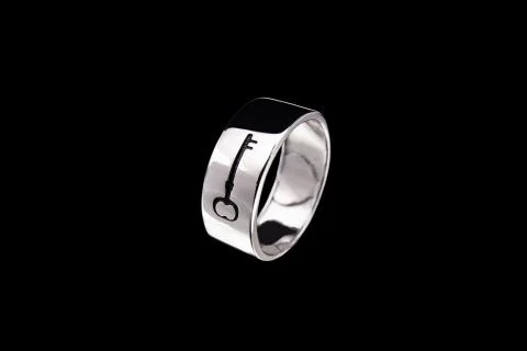Silver ring with key pattern on a black background Stock Photos