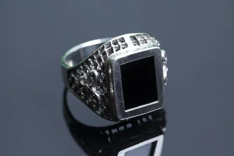Silver ring with a precious stone on a black background with reflection Foto stock