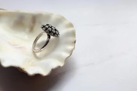 Silver ring with precious stones on a shell, marble background Stock Photos