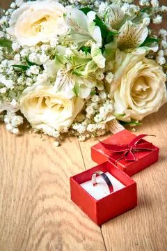 Silver ring in red gift box, bouquet of white flowers on wooden background, h Stock Photos