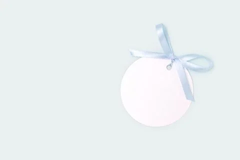 Silver round empty tag with tied blue ribbon bow. Stock Photos