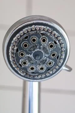 Silver round shower head with hard water deposit all around the sprinklers cl Stock Photos